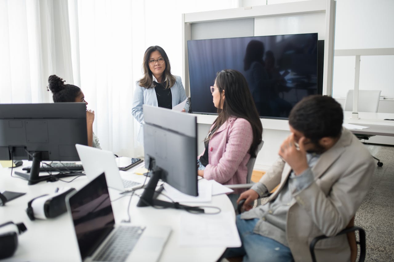 Professional team collaborating in a modern office environment with computers and screens.